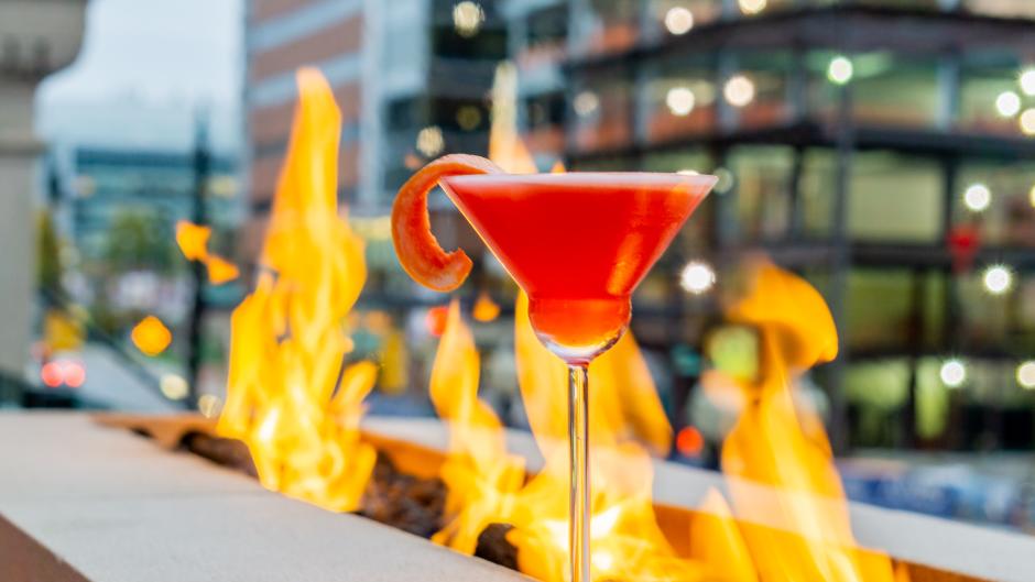A red cocktail at IDC's patio, positioned in front of an outdoor fire pit.