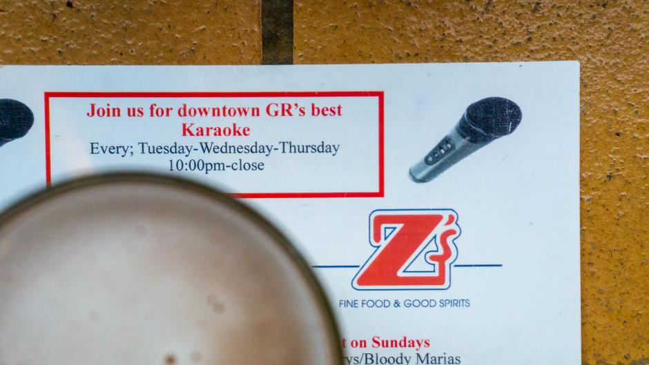 A beer glass sitting on a menu at Z's which says "Join us for downtown GR's best Karaoke."