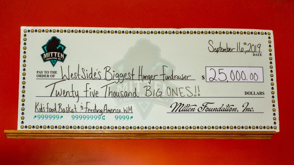 A giant check at The Mitten with the amount and charity of their monthly donation.