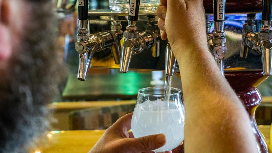 Bartender pouring hard seltzer from a tap into a glass.