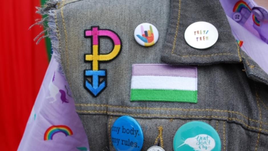Up close view of Pride buttons on a vest of a Pride Festival attendee
