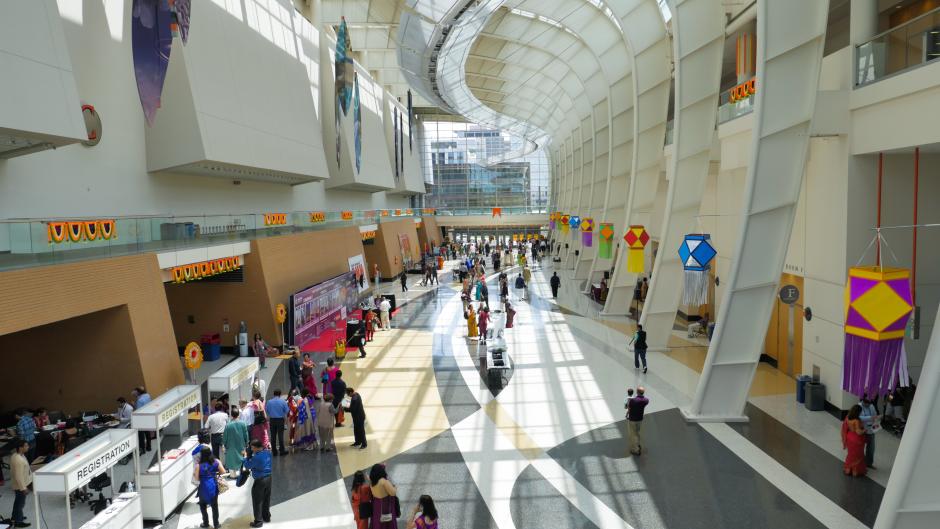 People visiting various exhibitor tables during a conference at a convention center in Grand Rapids