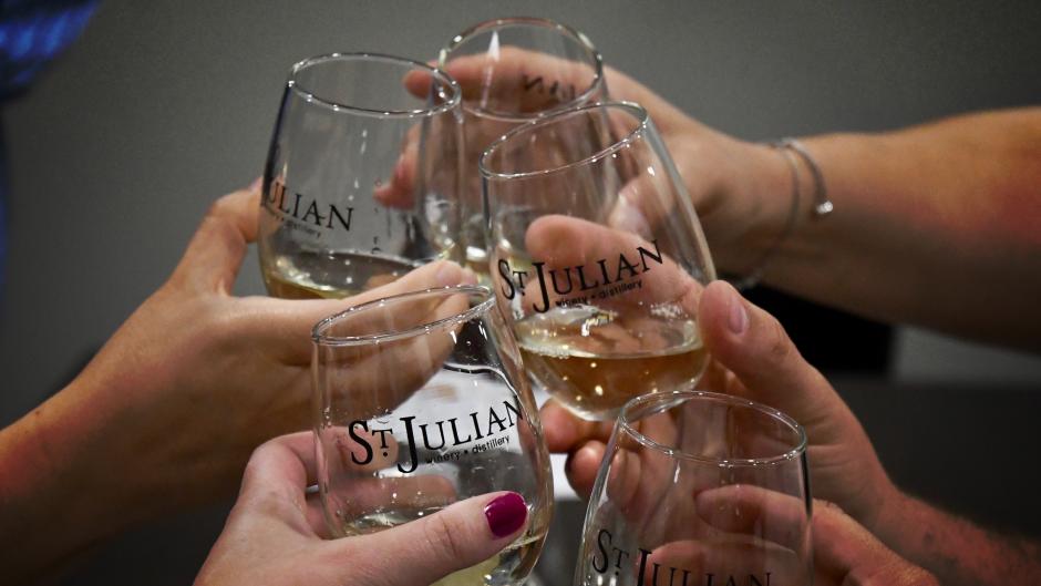 Glasses clinking at St. Julian Winery during Raise a Glass Wine Tour