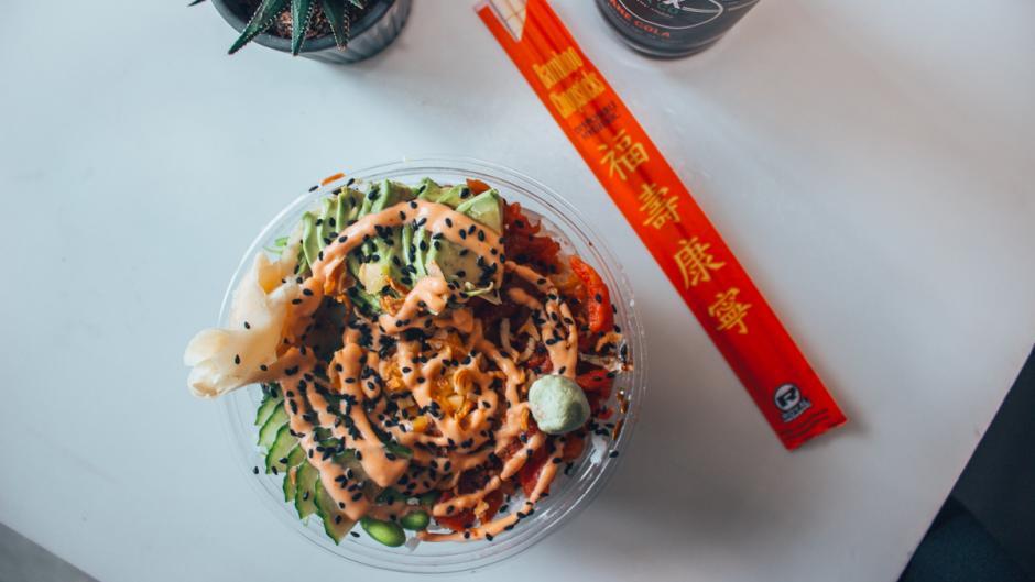 Bird's-eye view of a table holding a poke bowl, chopsticks, a soda, and a succulent.