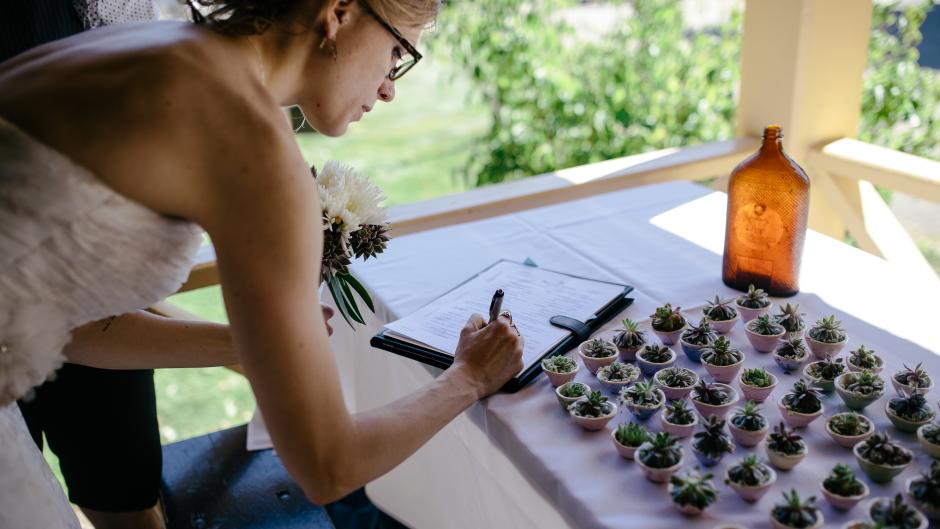 Bride signing next to succulent party favors.