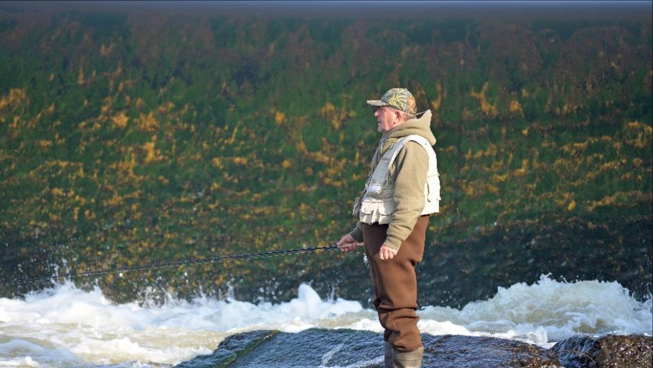 An angler fishes from the rocks immediately downstream of the Sixth St. Dam