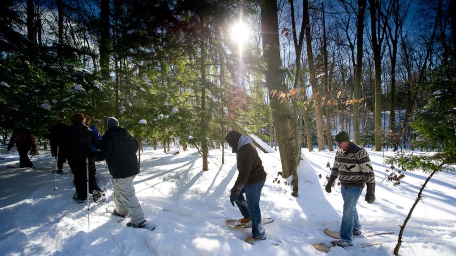 A group enjoys a guided snowshoe hike at P.J. Hoffmaster State Park where wooden snowshoes can be rented.