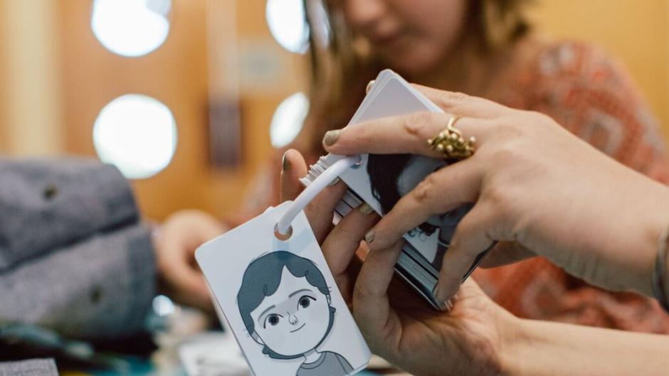 Child holding out the happy card from her feelings cards deck