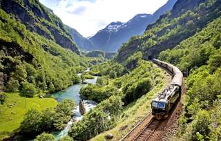 The Flåm railway going through the landscape of green hills and spectacular mountains in Fjord Norway