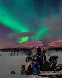 Man on a snowmobile under the northern lights