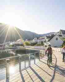 Plan your trip to the Sognefjord area: Two women are biking along the Fjordstien path in Sogndal by the Sognefjord in Fjord Norway