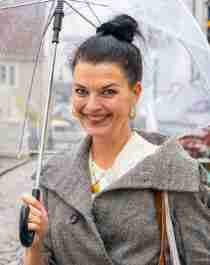 A woman stands under an umbrella in the Pedersgata street in Stavanger, Fjord Norway.