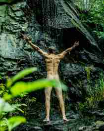 A man showering naked under a waterfall in Innerdalen, Norway