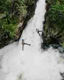 Couple ziplining over waterfall in Geiranger