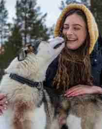 A woman cuddling with a sled dog at Geilo in the winter.