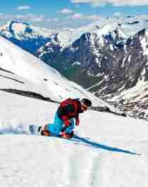 En person står på snowboard ned fjellsiden i Stryn