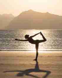 Una mujer practica yoga en silencio en una playa en Lofoten, Norte de Noruega.