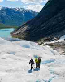 Three people hiking on the Nigardsbreen glacier in Fjord Norway