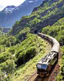 The Flåm Railway going through the landscape of green hills and spectacular mountains in Fjord Norway