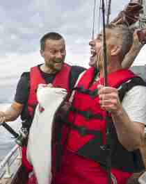 To menn fisker fra en båt i Tromsø