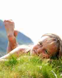 Una niña descansa sobre la hierba de un soleado día de verano en Hovden, Setesdal.