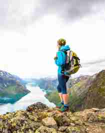En dame står på toppen av Besseggen og ser utover Gjende i Jotunheimen
