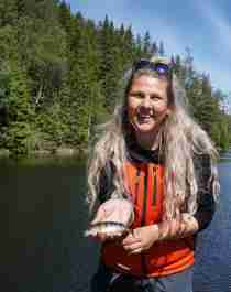 Eine Frau, die einen kleinen Fisch im Anglerparadies Norwegen hält.