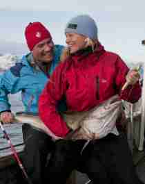 Eine Frau und ein Mann mit einem frisch gefangenen Kabeljau auf den Lofoten in Nordnorwegen