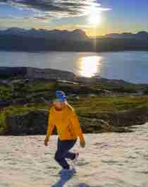 A woman is enjoying a late hike under the midnight sun in Narvik, Northern Norway