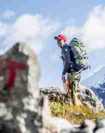 A man hiking past a safety cairn in the mountains