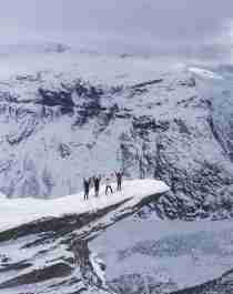 Un grupo de cuatro personas con raquetas de nieve disfruta las vistas desde lo alto de Trolltunga, en la Noruega de los fiordos, en un día de invierno.