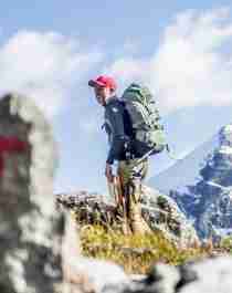 A man hiking past a safety cairn in the mountains