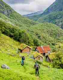Två personer går mot fjällgården Avdalen i Utladalen, Fjord Norge