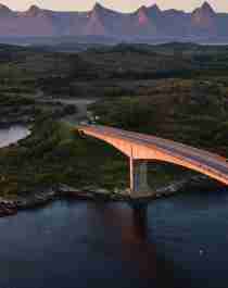 En bro förbinder Herøy med en annan ö i Helgeland, Nord-Norge. I bakgrunden syns bergen De syv søstre (De sju systrarna)