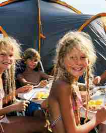 Kinder, die vor einem Campingzelt bei Hamre familiecamping in Kristiansand, Südnorwegen, essen