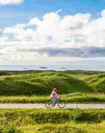En kvinne sykler på Nasjonal Turistveg Andøya