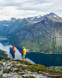 A couple enjoying the view of the Hjørundfjord on a hike in Møre og Romsdal, Fjord Norway