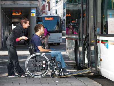 A man in a wheelchair is assisted on a bus