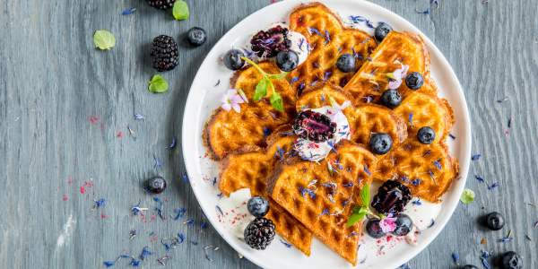 A plate of waffles with sour cream and berries