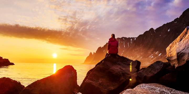 A person watching the midnight sun at Senja in Northern Norway