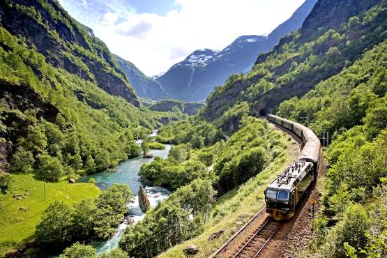 The Flåm railway going through the landscape of green hills and spectacular mountains in Fjord Norway