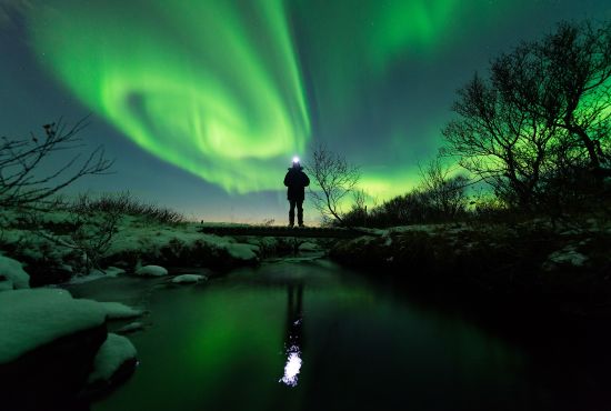 A man standing out in nature, watching the northern lights in Varanger