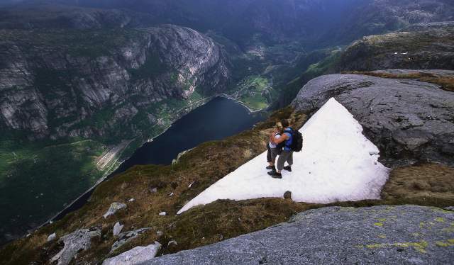 Couple on Mount Kjerag in Fjord Norway admiring view of the Lysefjord