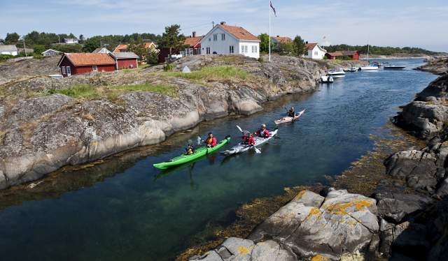Una famiglia in kayak attraverso uno stretto nell’arcipelago di Risør, Norvegia meridionale