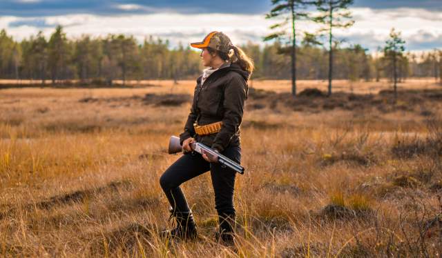 En kvinne jakter i skogen om høsten