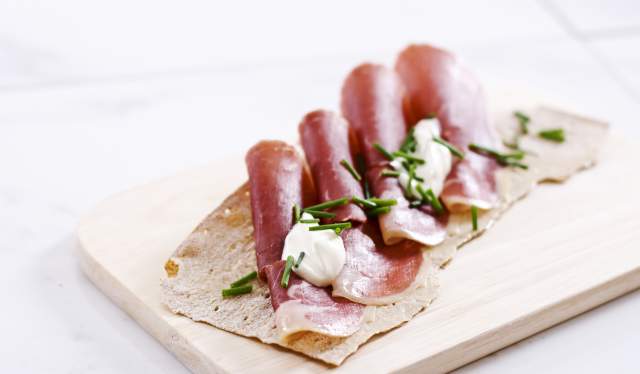 Norwegian flatbrød (flat-bread) served with sliced fenalår served on a wooden platter in Norway