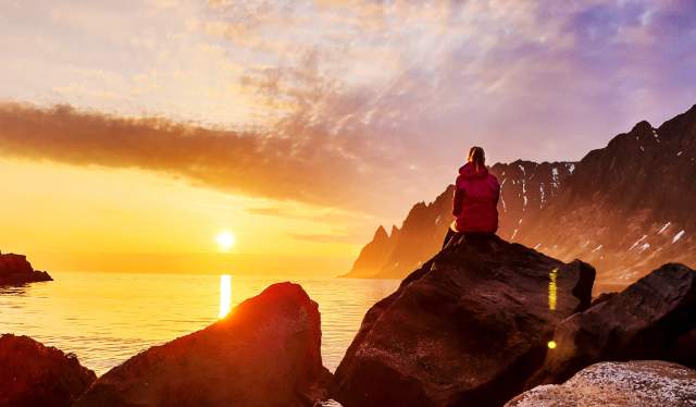 A person watching the midnight sun at Senja in Northern Norway