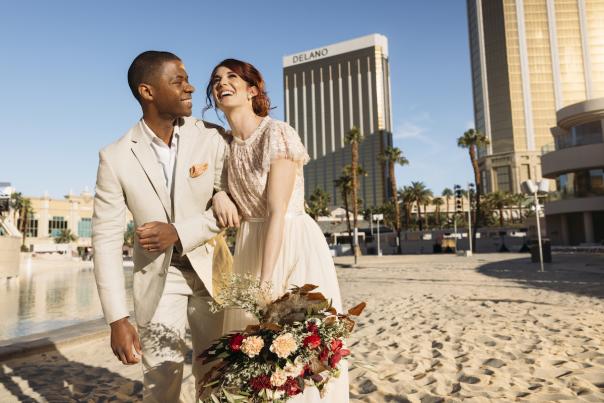 A couple gleefully walking on the pristine sands of Mandalay Bay after their wedding.