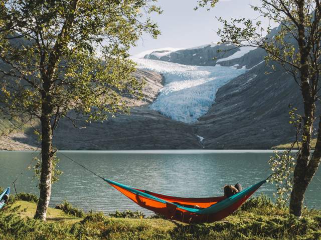 People in hammocks in front of the Svartisen glacier in Helgeland, Northern Norway