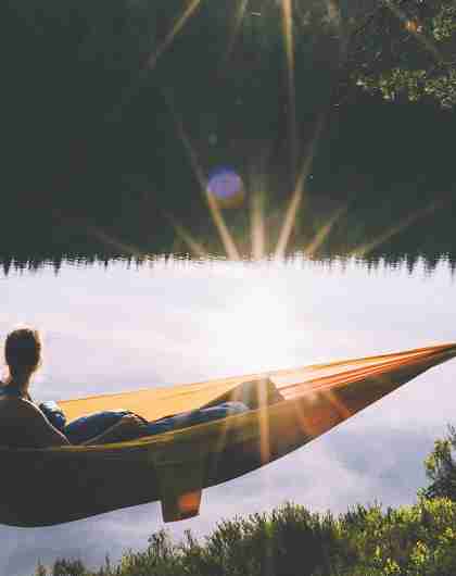 A woman relaxing in a camping hammock while during sunset in Nordmarka forest in Oslo, Eastern Norway